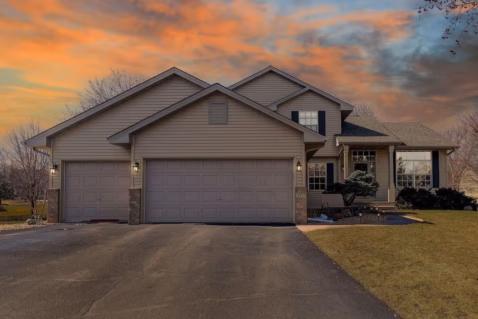 Front view of a large residential house with a three-car garage at sunset.