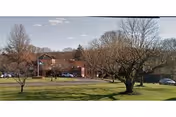 Front exterior view of Montowese Center for Health & Rehabilitation with trees and parked cars.