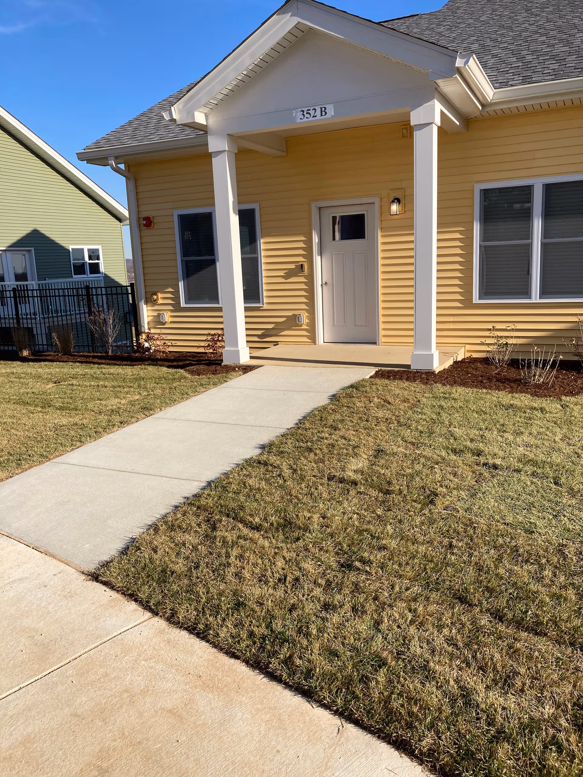 Yellow house-style senior living facility entrance with white door and columns