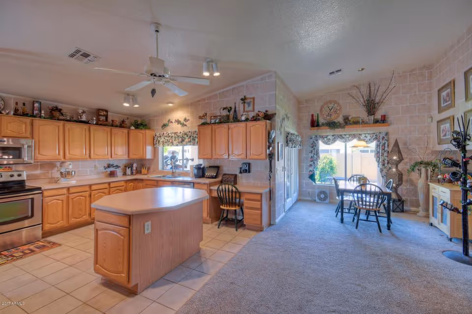 Bright kitchen with wooden cabinets, island, and dining area in a residential facility.