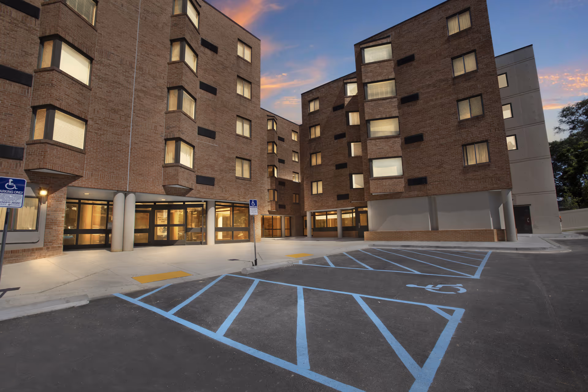 Exterior of Lakeland Seniors Apartments, brick, multi-story building with glass entrance and accessible parking.