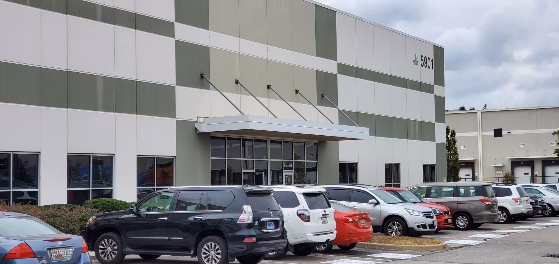 Exterior view of a modern building with a glass entrance and many parked cars.