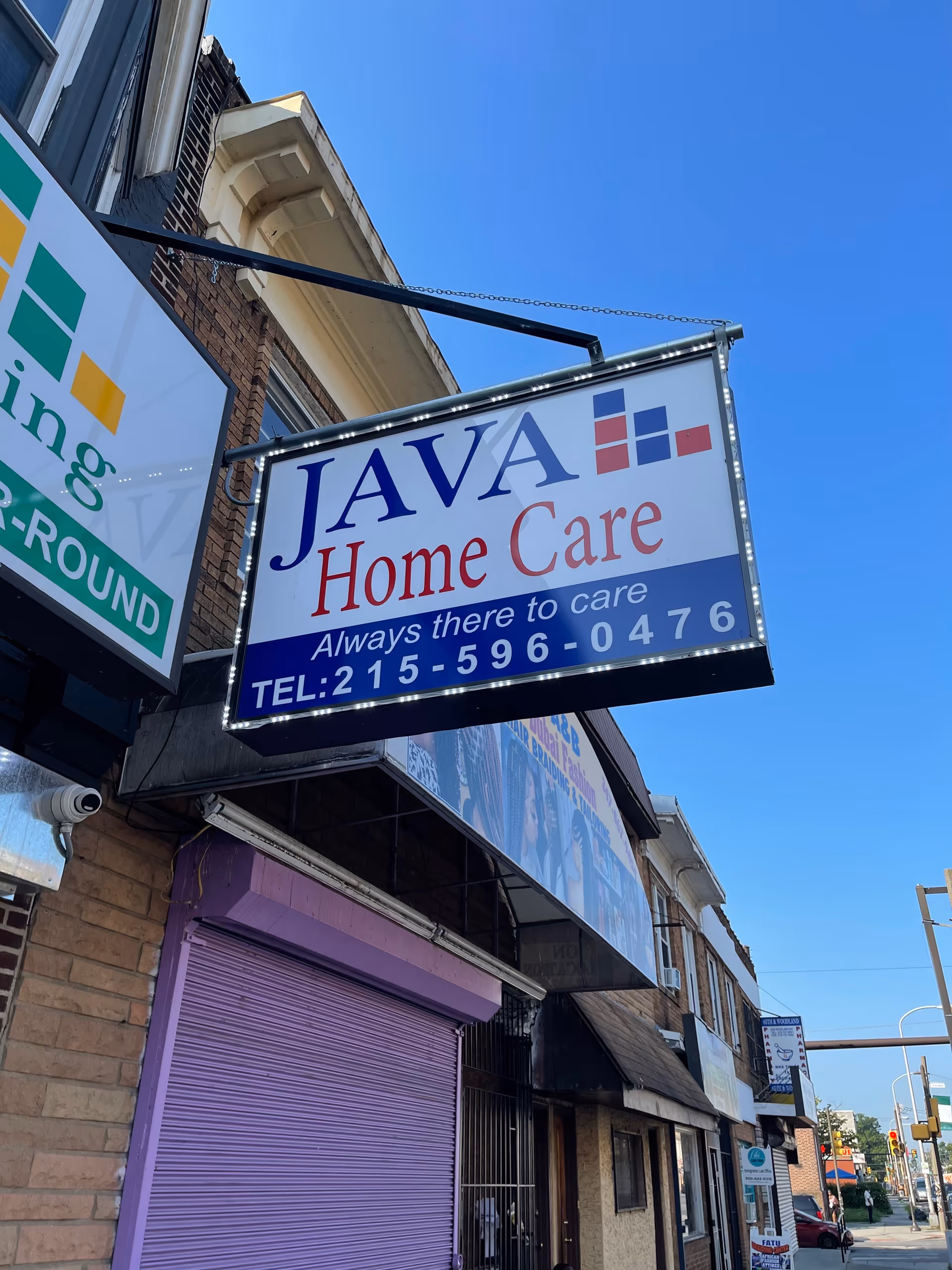 Storefront sign reads JAVA Home Care hanging from a building against a blue sky