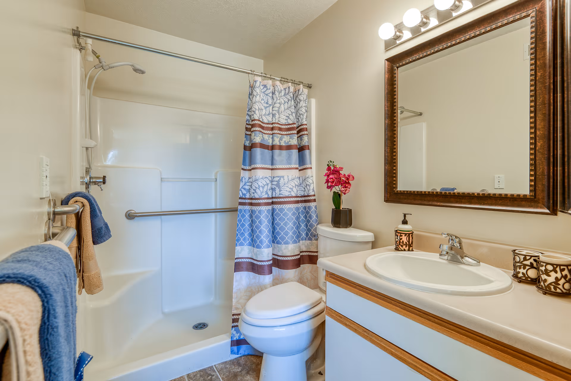 Accessible bathroom with a tub/shower, grab bars, a vanity sink, and mirror.