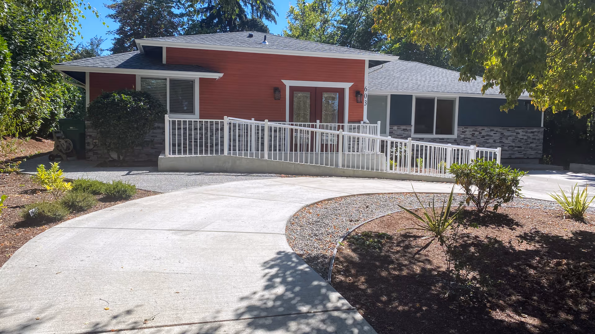 Single-story building with a ramped entrance, white railing, and landscaped front yard.