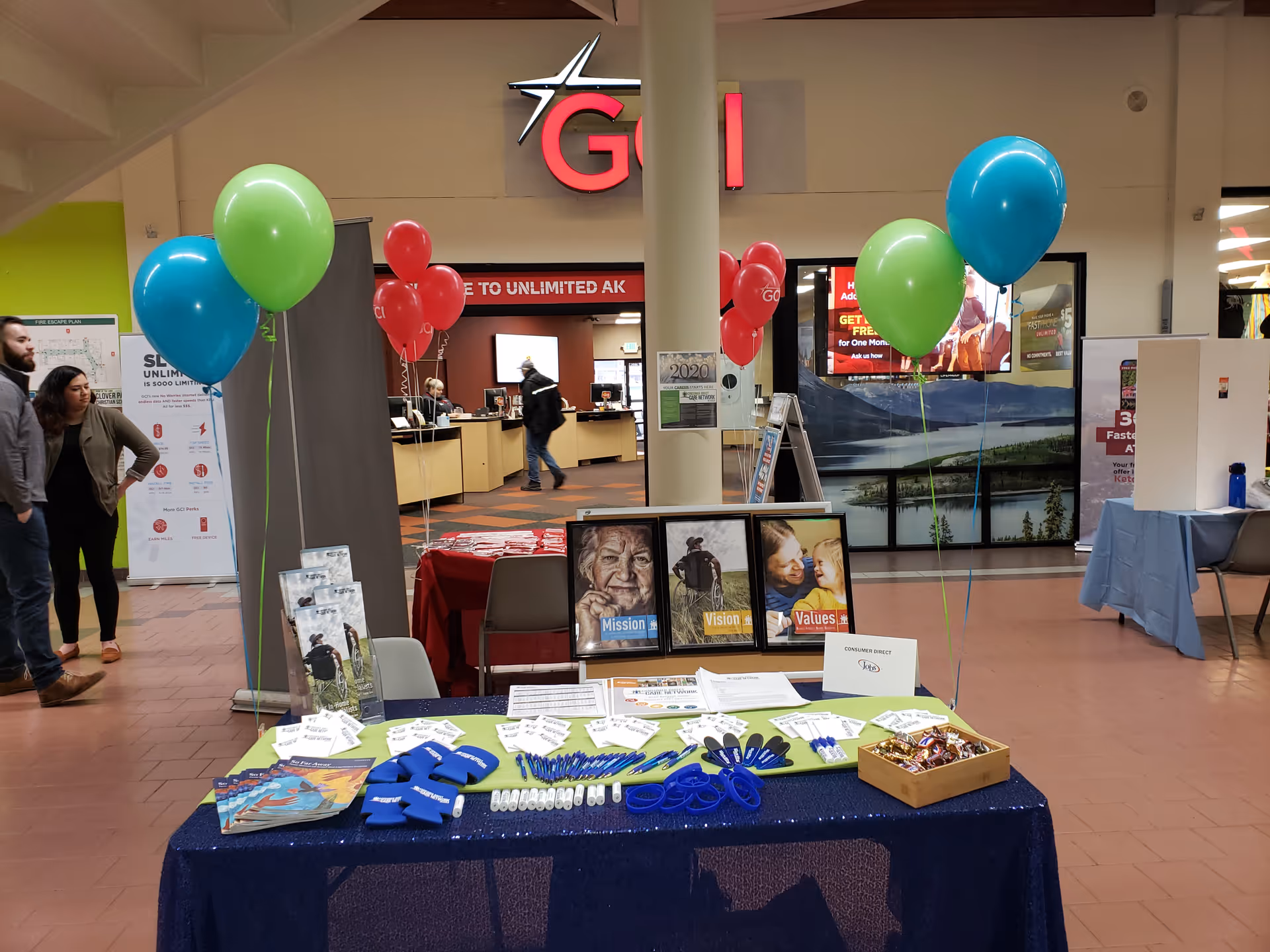 Indoor facility lobby with balloons, a staffed information table, and promotional displays.