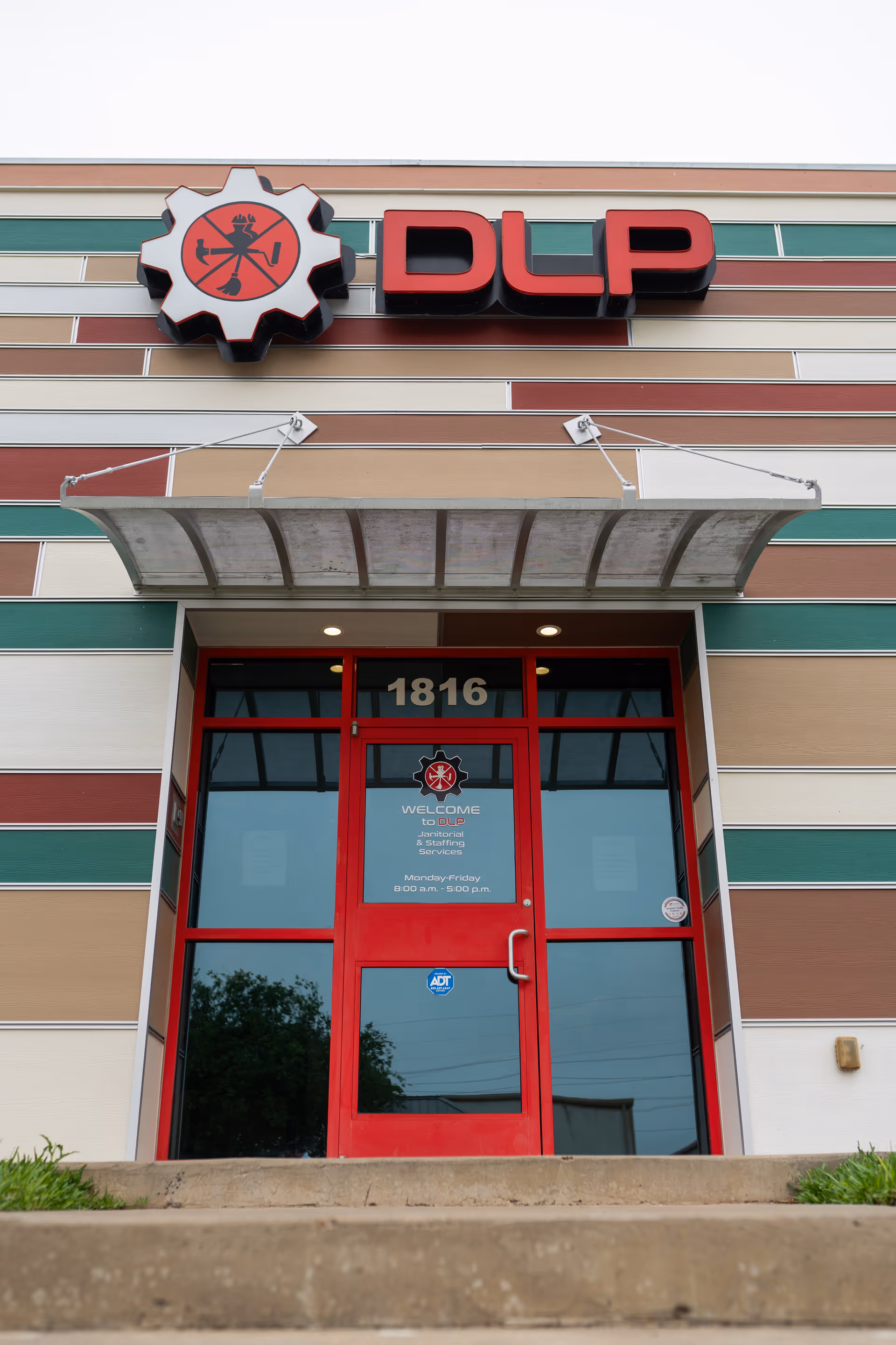 Exterior view of the DLP Services LLC building front with striped panels and red entrance doors.