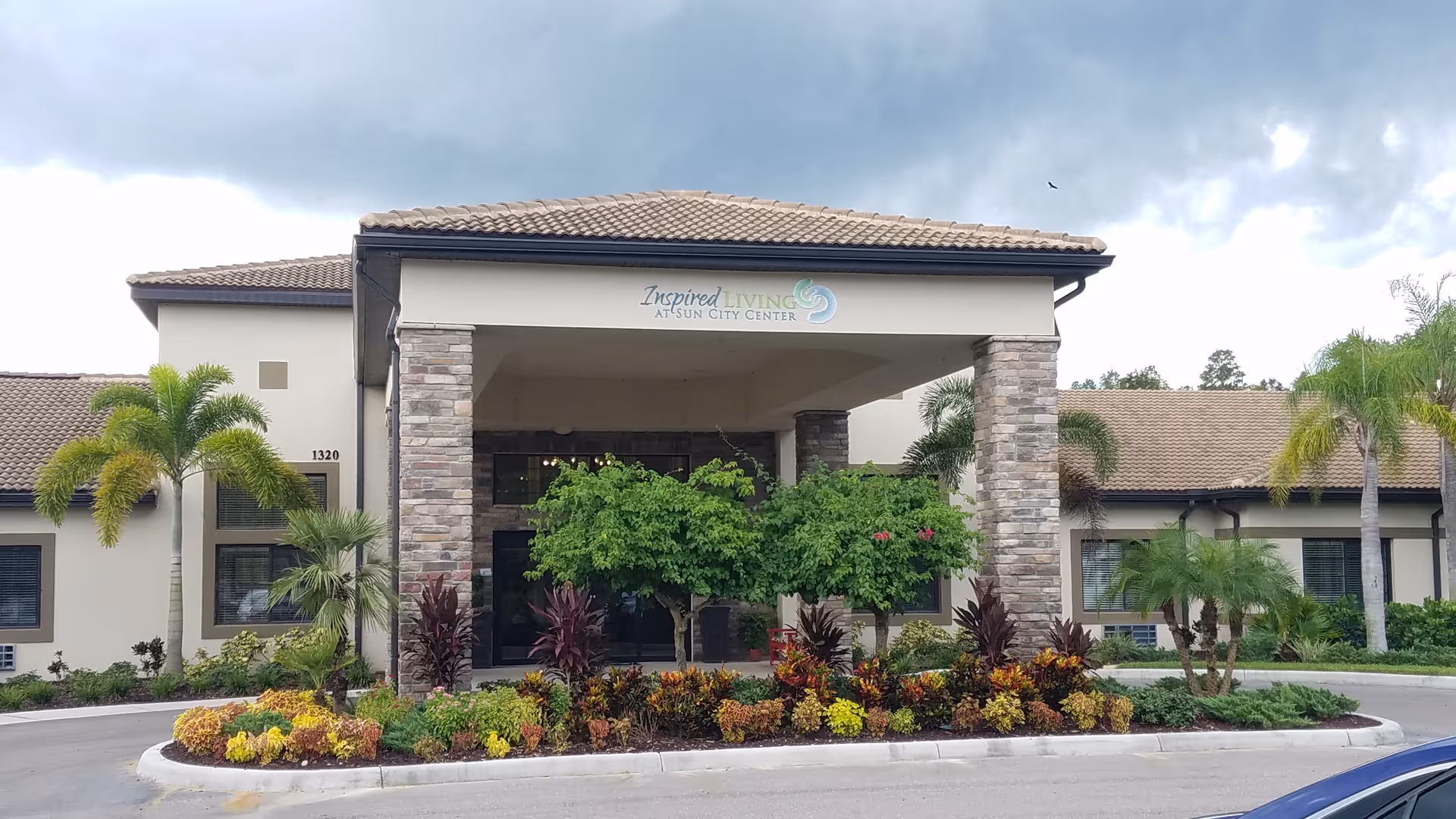 Senior living facility entrance with stone columns and landscaped front garden