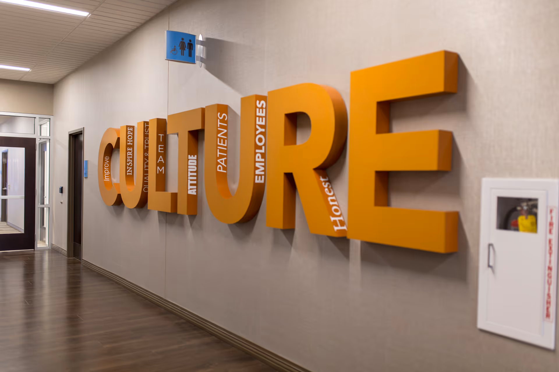 Indoor hallway with large orange letters spelling COURAGE on the wall.