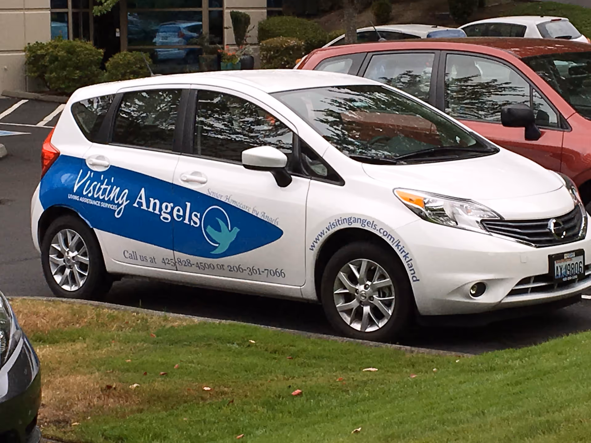White Visiting Angels care van with blue logo parked in a parking lot.