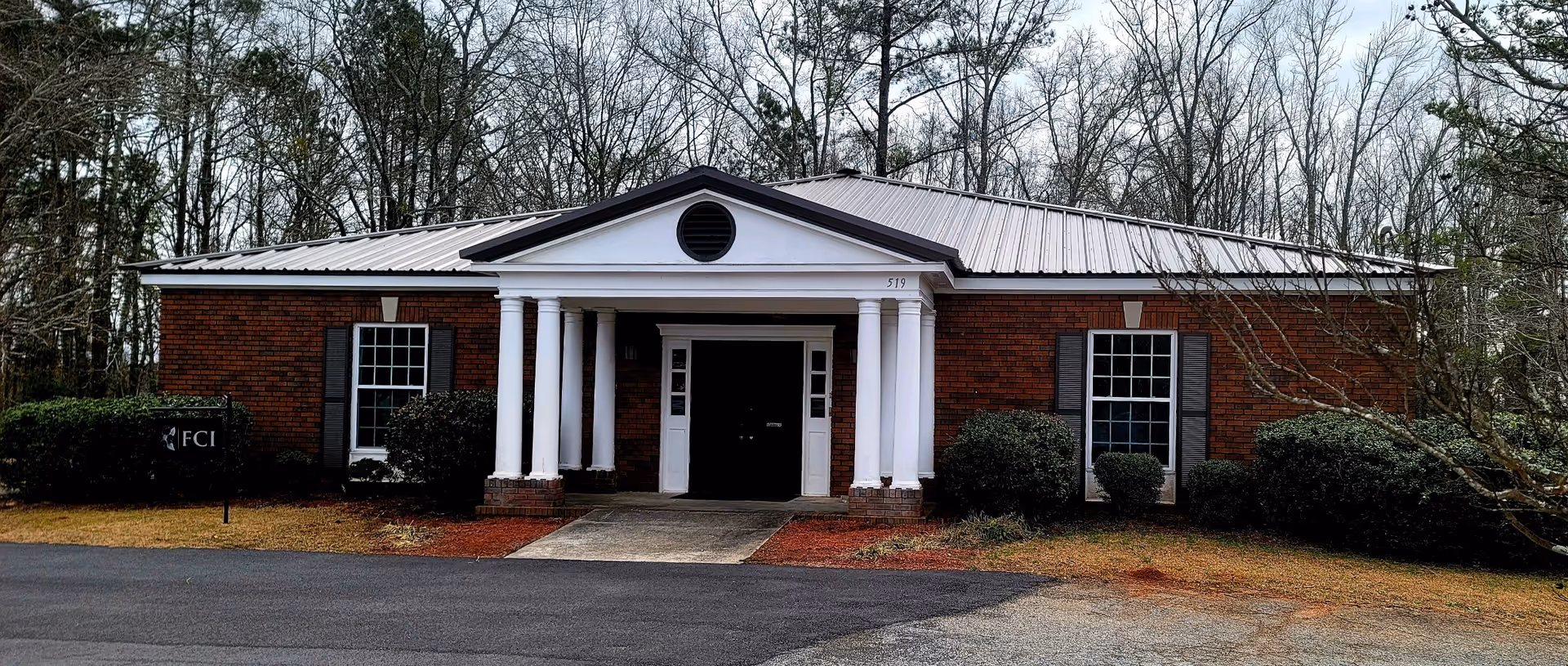 Brick senior care facility with a white columned entrance and shrubs.