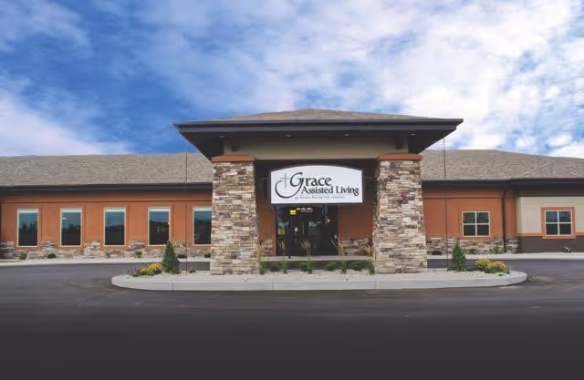 Exterior view of a senior living facility with a stone entrance and Grace Assisted Living sign.