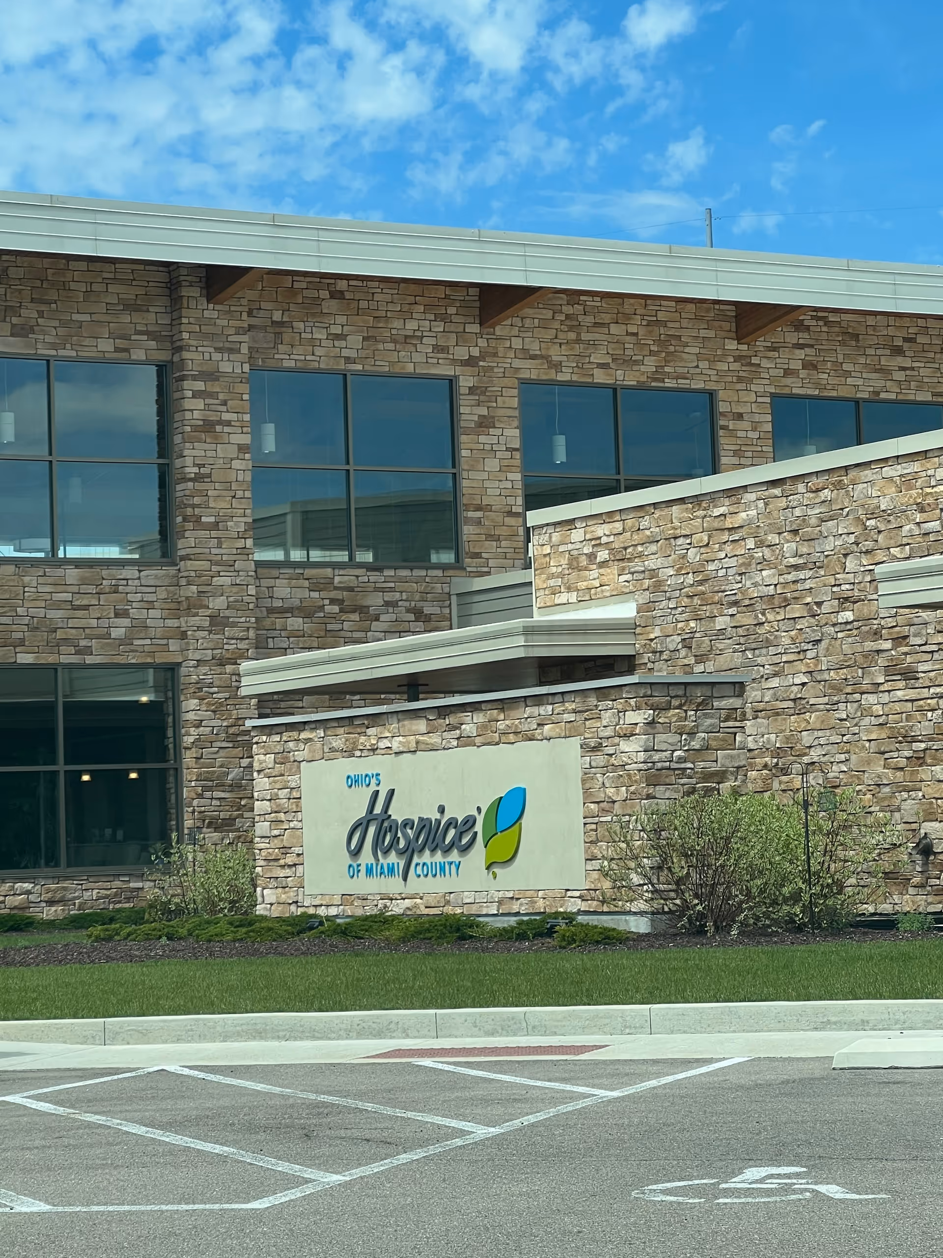 Exterior view of Ohio's Hospice of Miami County building with stone facade and sign.