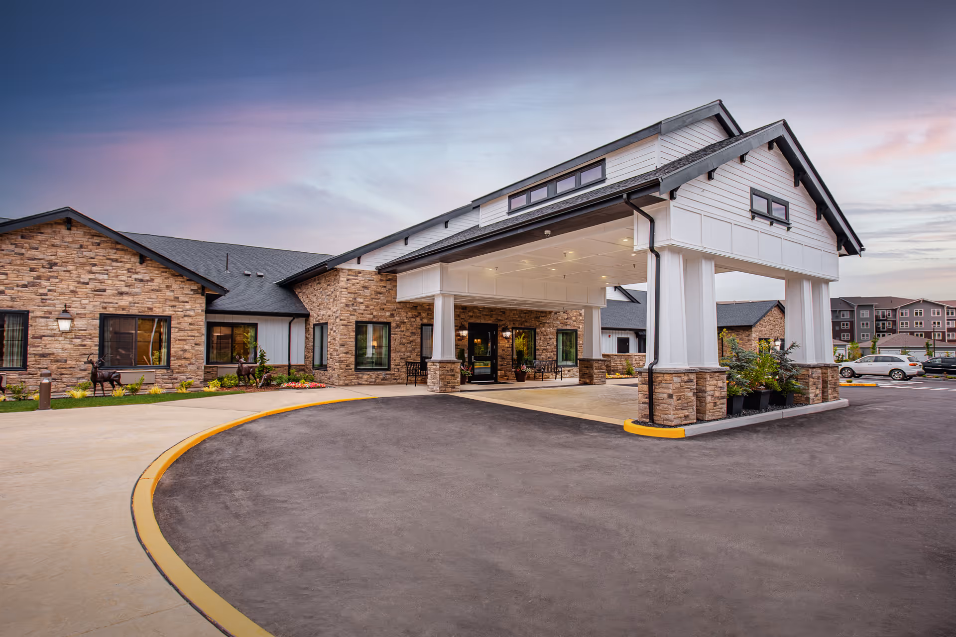 Exterior view of Deer Ridge Memory Care Community entrance with covered driveway and parking.