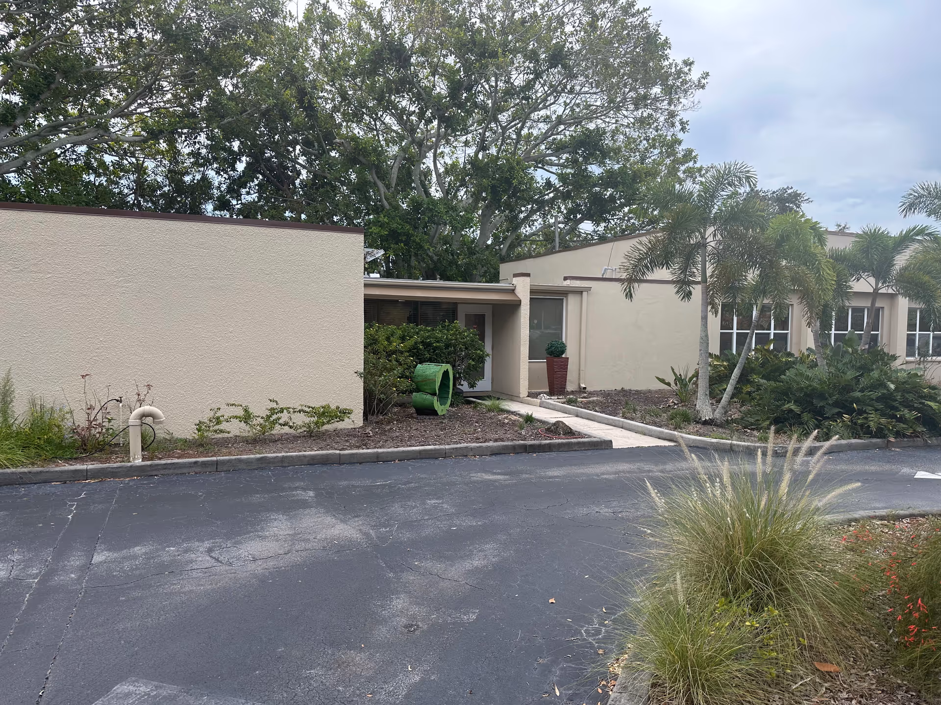 Exterior view of a beige, single-story facility with palm trees and a paved parking lot.