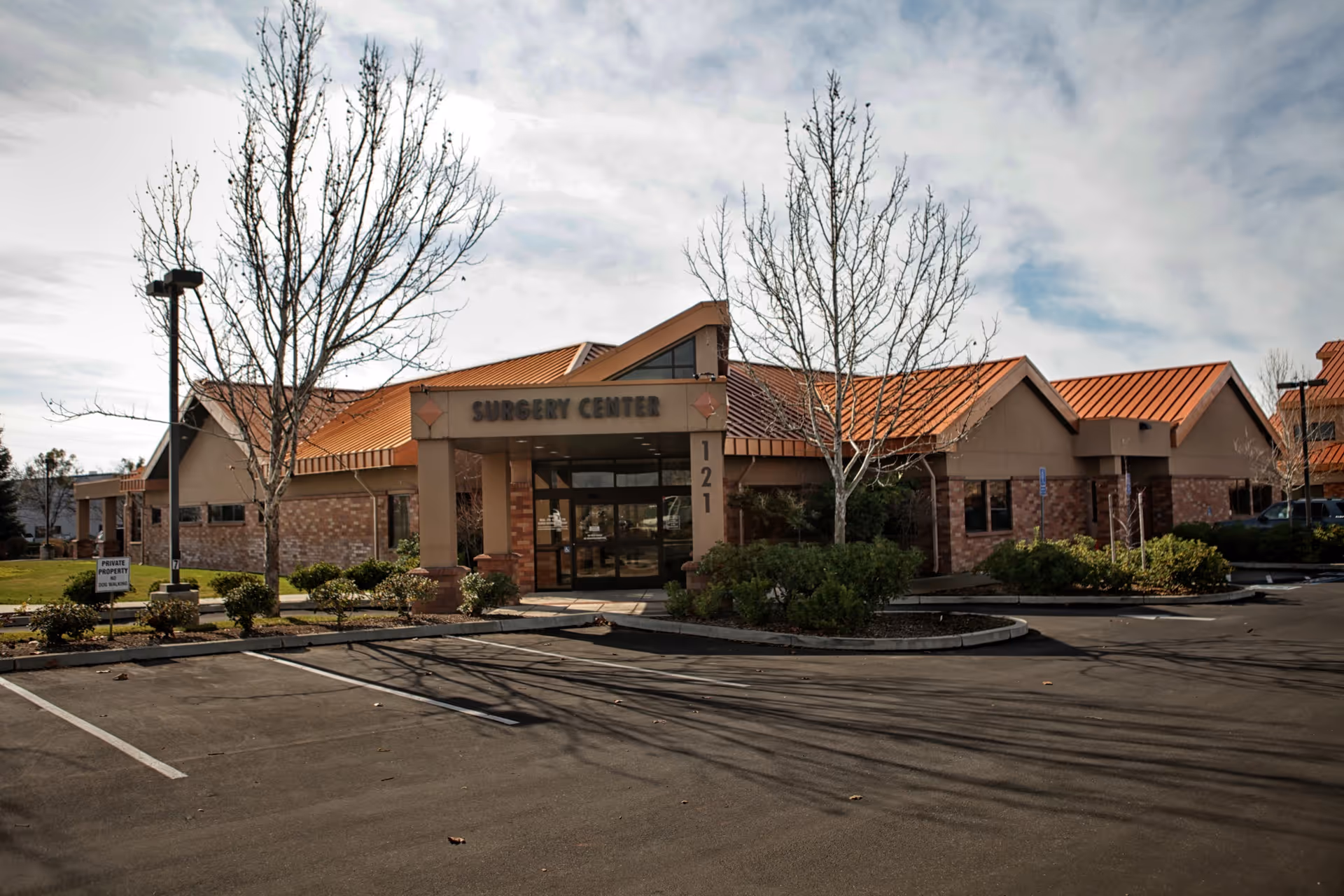 Exterior view of Skyway Surgery Center with red-tiled roof and a parking lot.
