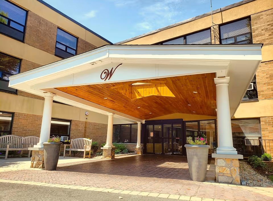 Entrance to Woonsocket Health & Rehab Center with a white portico and benches.