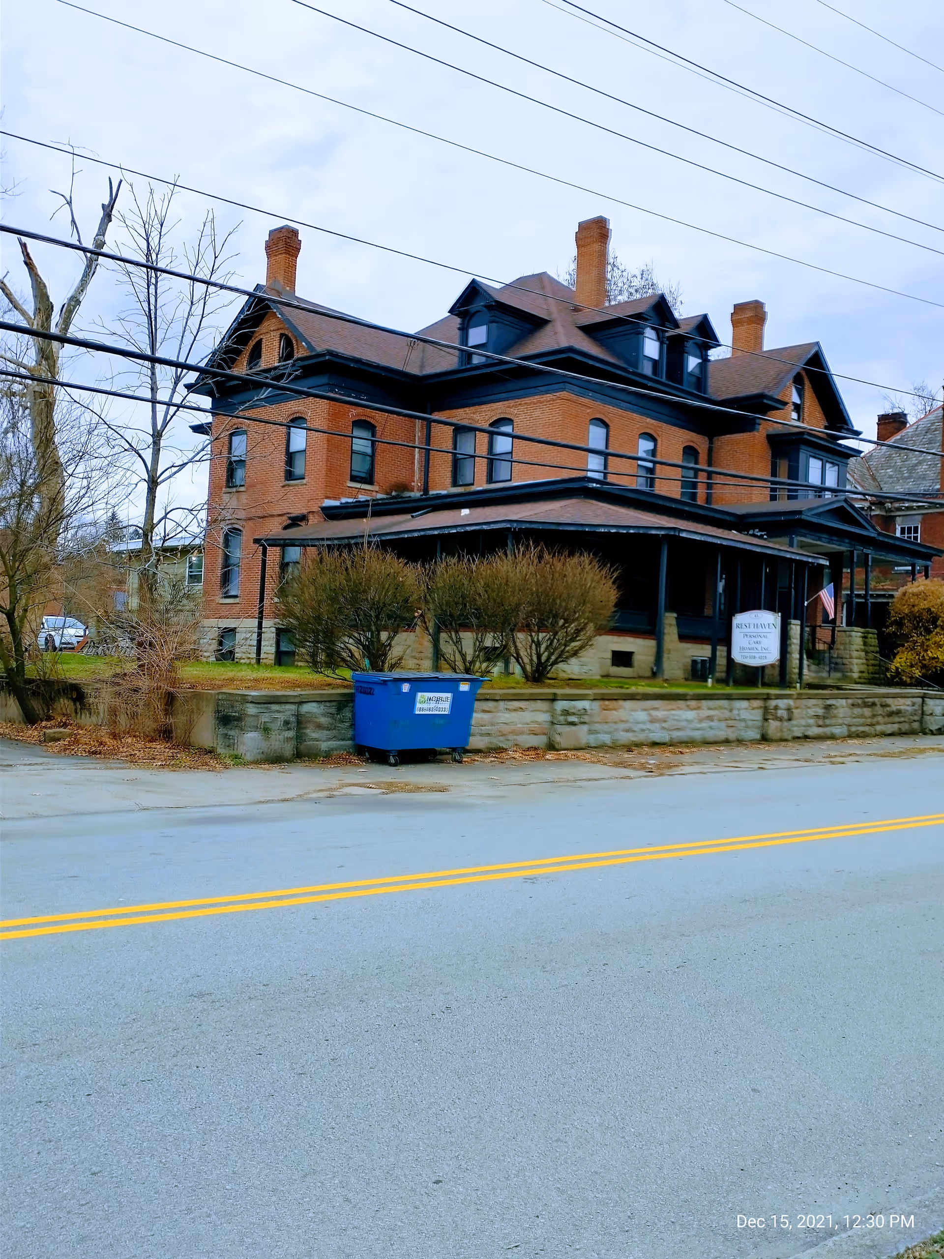 Exterior view of a brick senior living facility with porch and power lines.