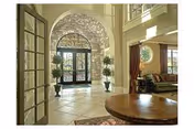 Elegant lobby with arched doorway, potted plants, and round wooden table.