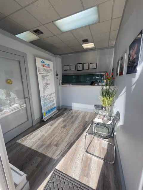 Narrow reception area with chairs on the right, a banner, and a front desk at back.