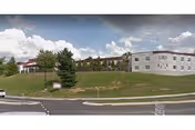 A Sundale Nursing Home building sits on a grassy hill beside a road.
