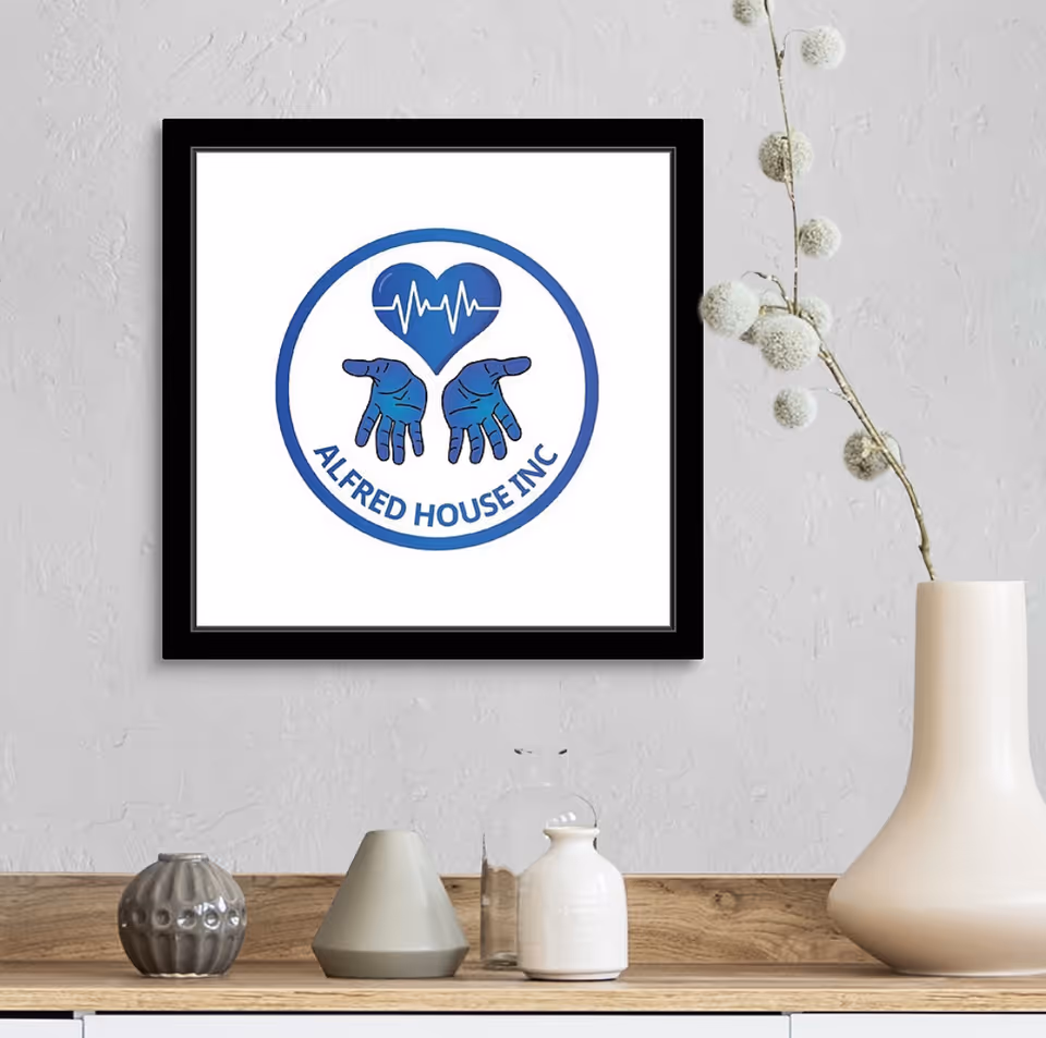 A framed Alfred House Inc logo hangs on a white wall above a wooden shelf