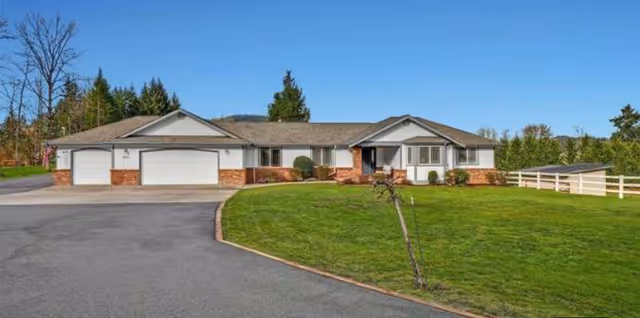 Front view of a single-story care home with three garages and a green lawn.