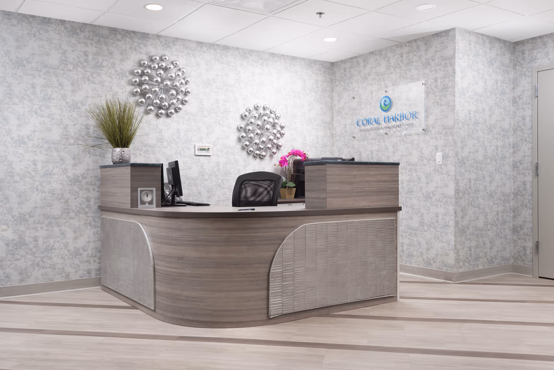 Modern reception desk in a light-colored lobby with wall decor and a Coral Harbor sign.