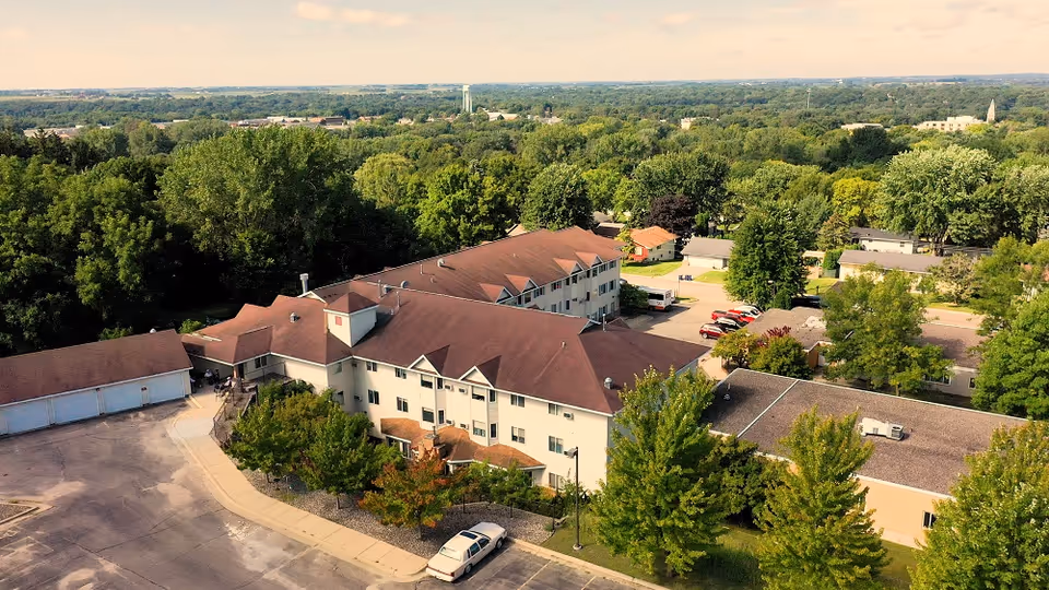 Aerial view of Pleasant View Estates senior living campus with beige buildings and surrounding trees.
