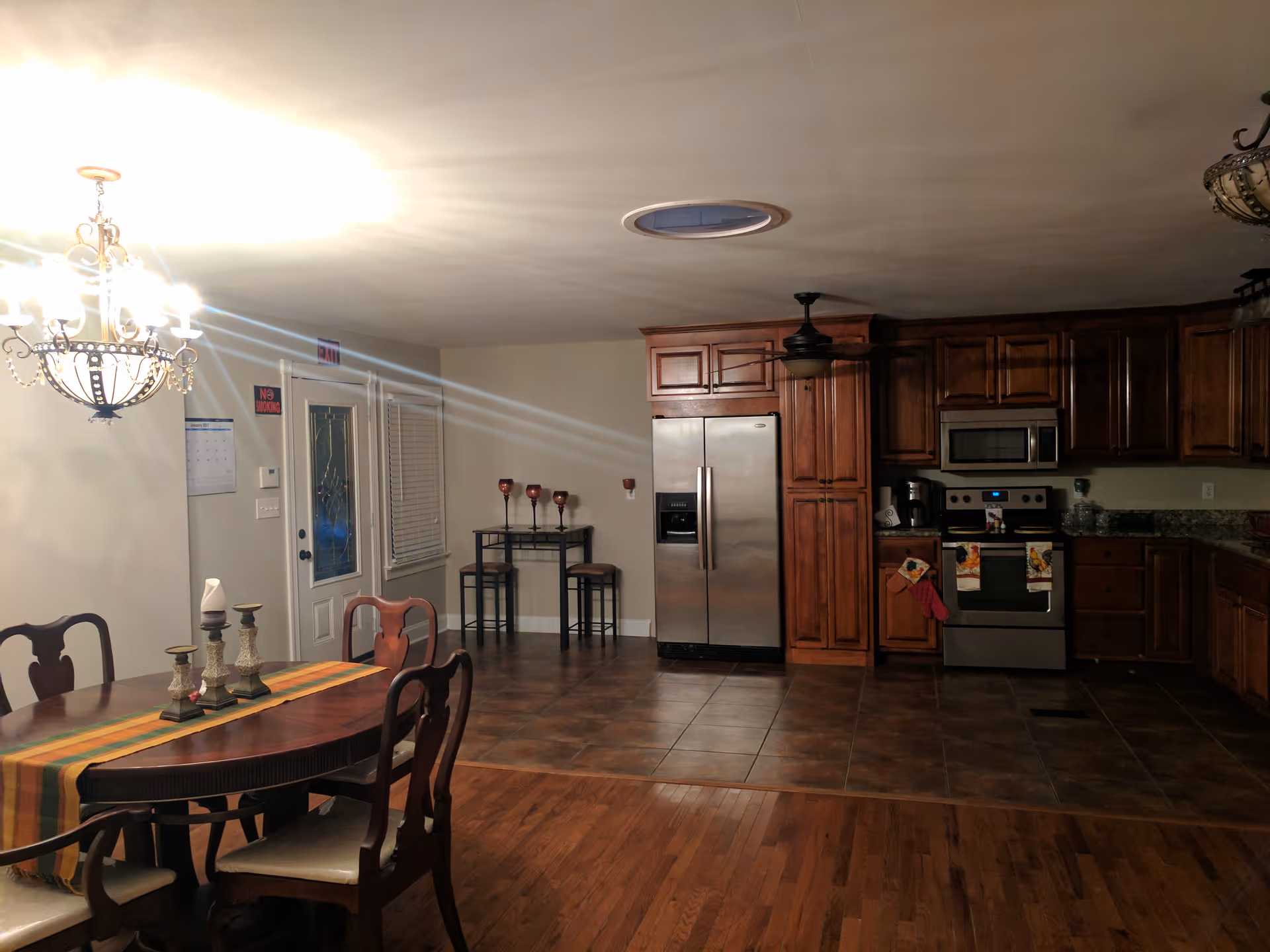 Spacious kitchen with stainless appliances, dark wood cabinets, and a dining table nearby.
