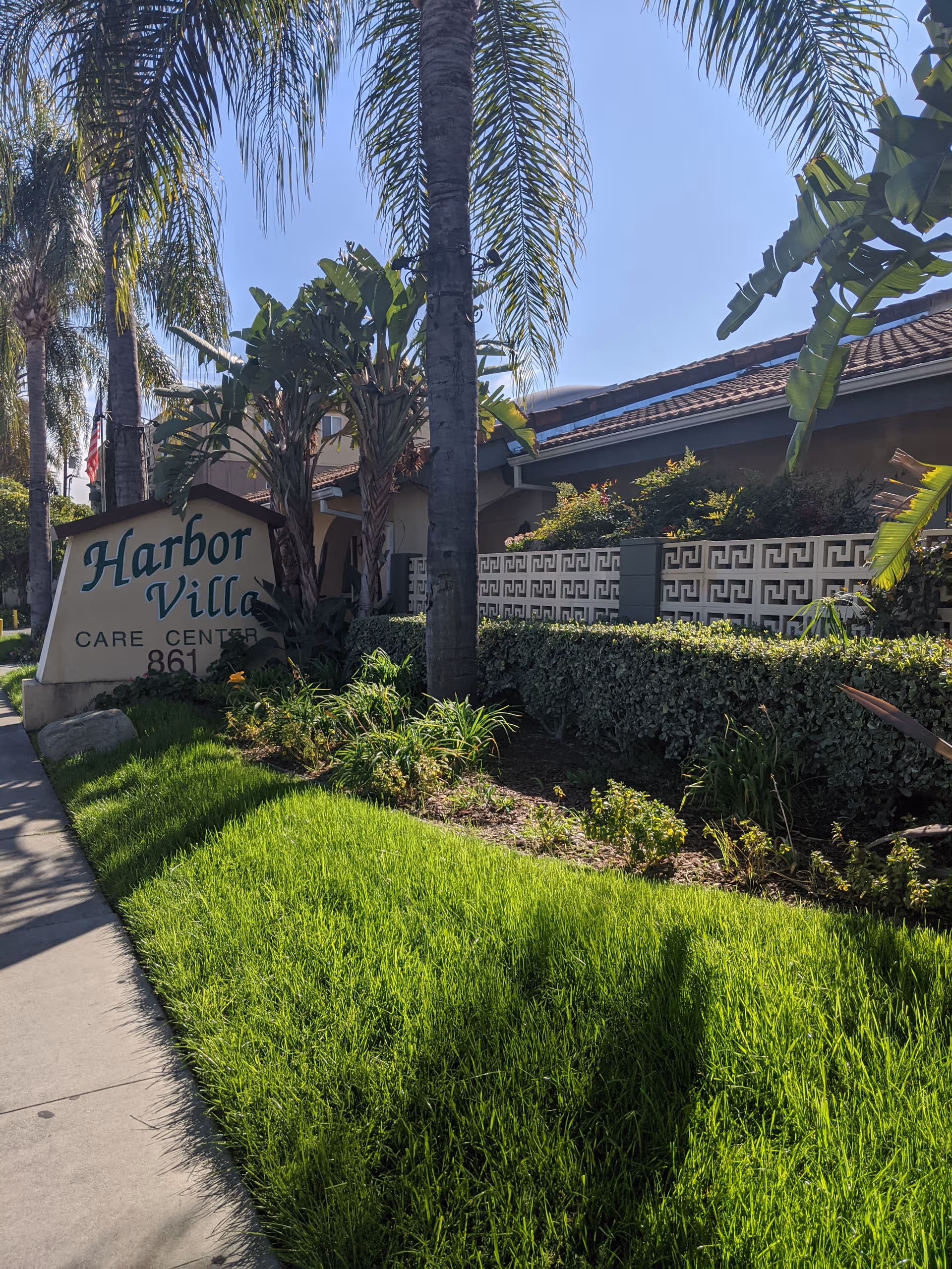 Harbor Villa Care Center sign near a landscaped front entrance with tall palm trees