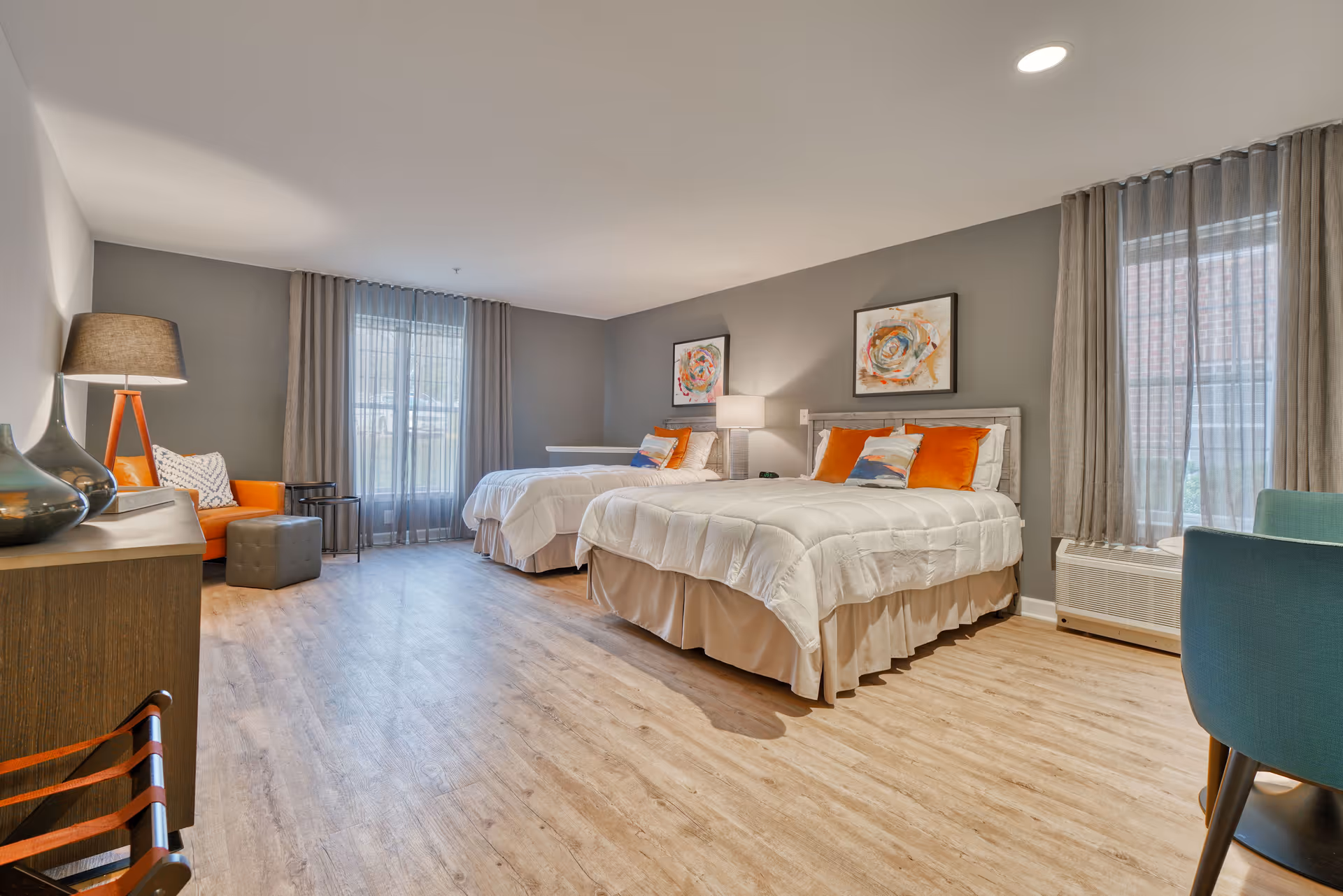 Two queen beds with white bedding and gray walls in a furnished senior living bedroom.