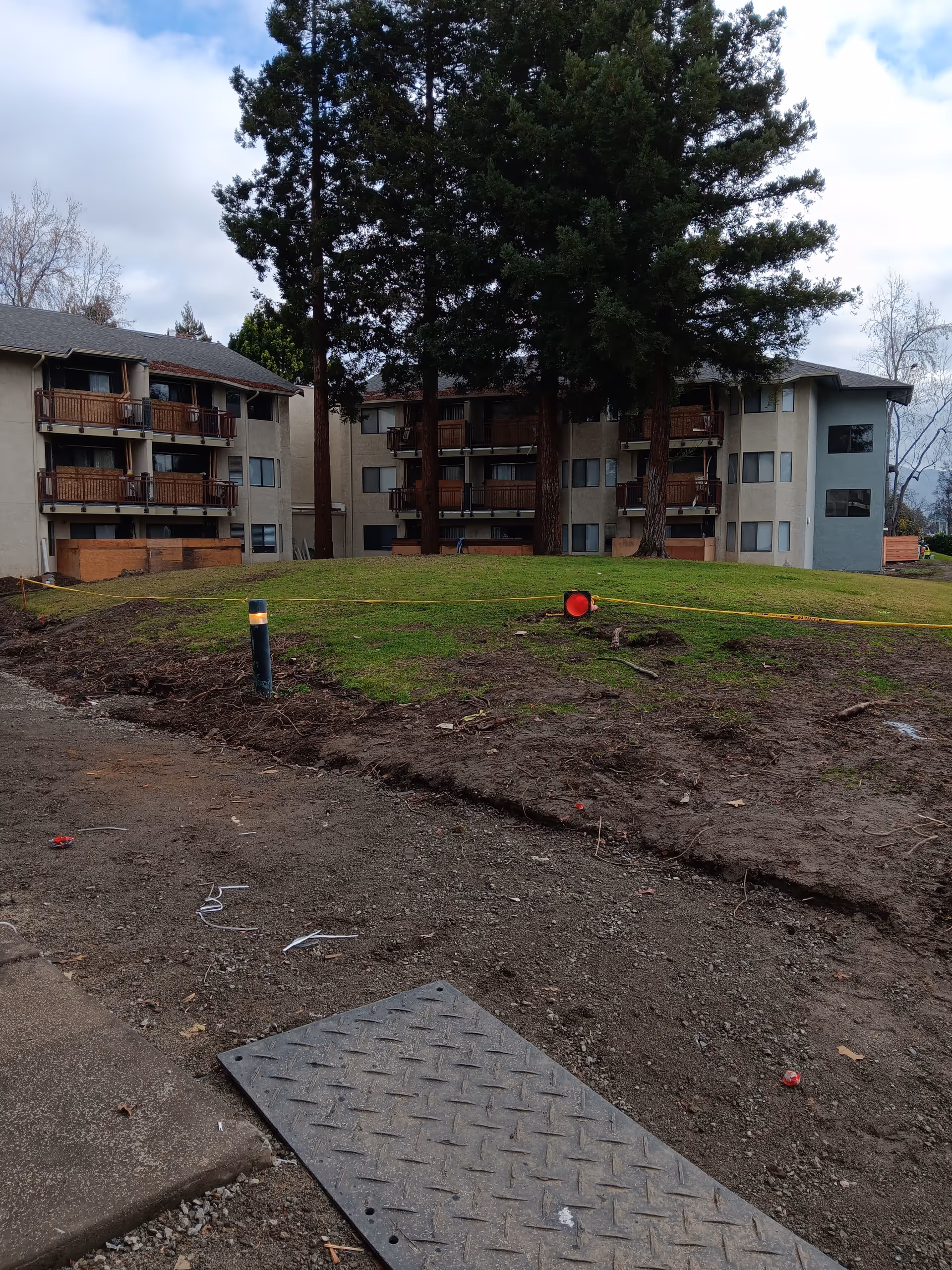 Three-story senior living building with balconies sits behind a dirt foreground.