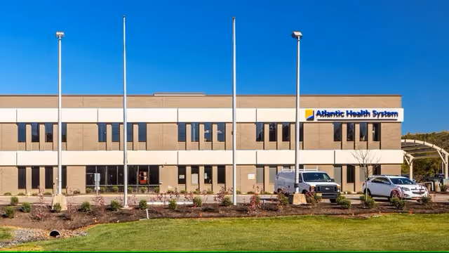 Front exterior of Atlantic Health System Bridgewater Pavilion with parked cars and blue sky