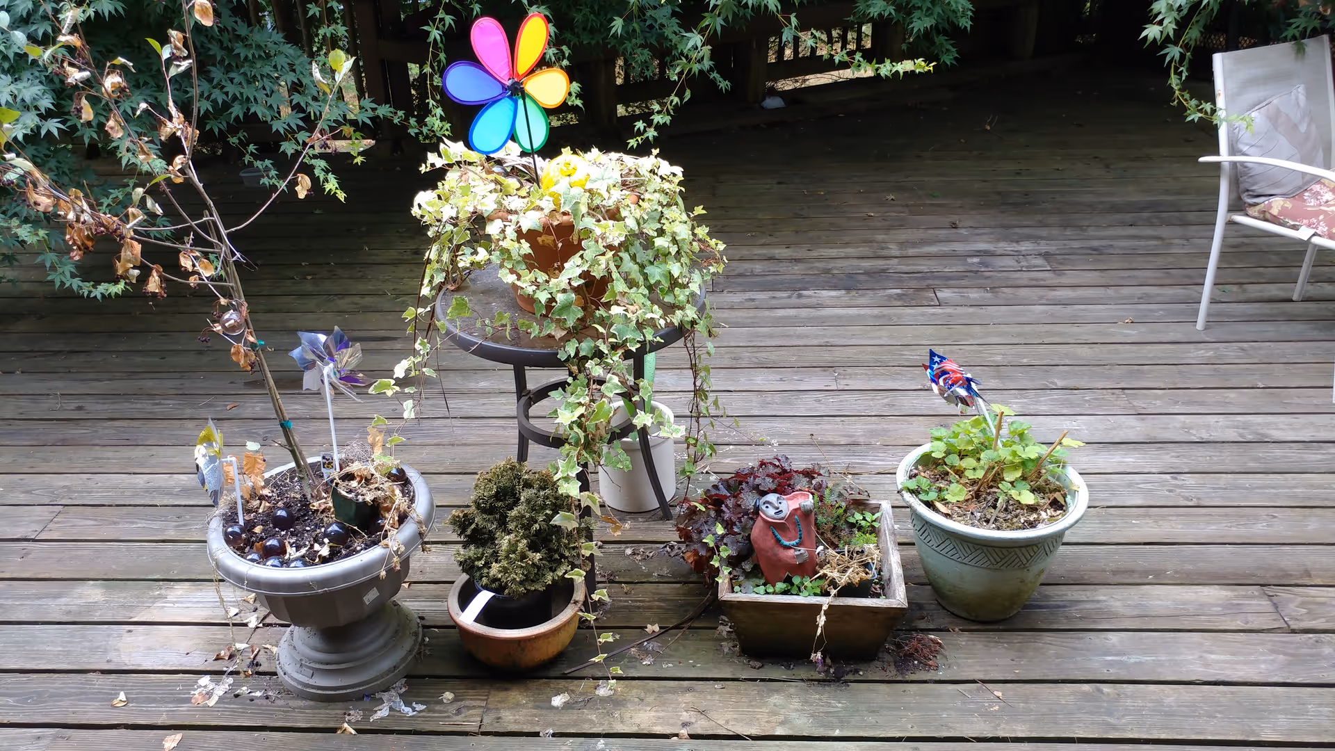 Outdoor wooden deck with potted plants, garden ornaments, and a chair.