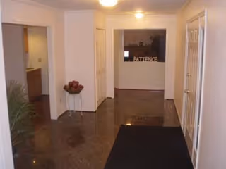 Hallway in a senior living facility with a reception desk and doorway openings.