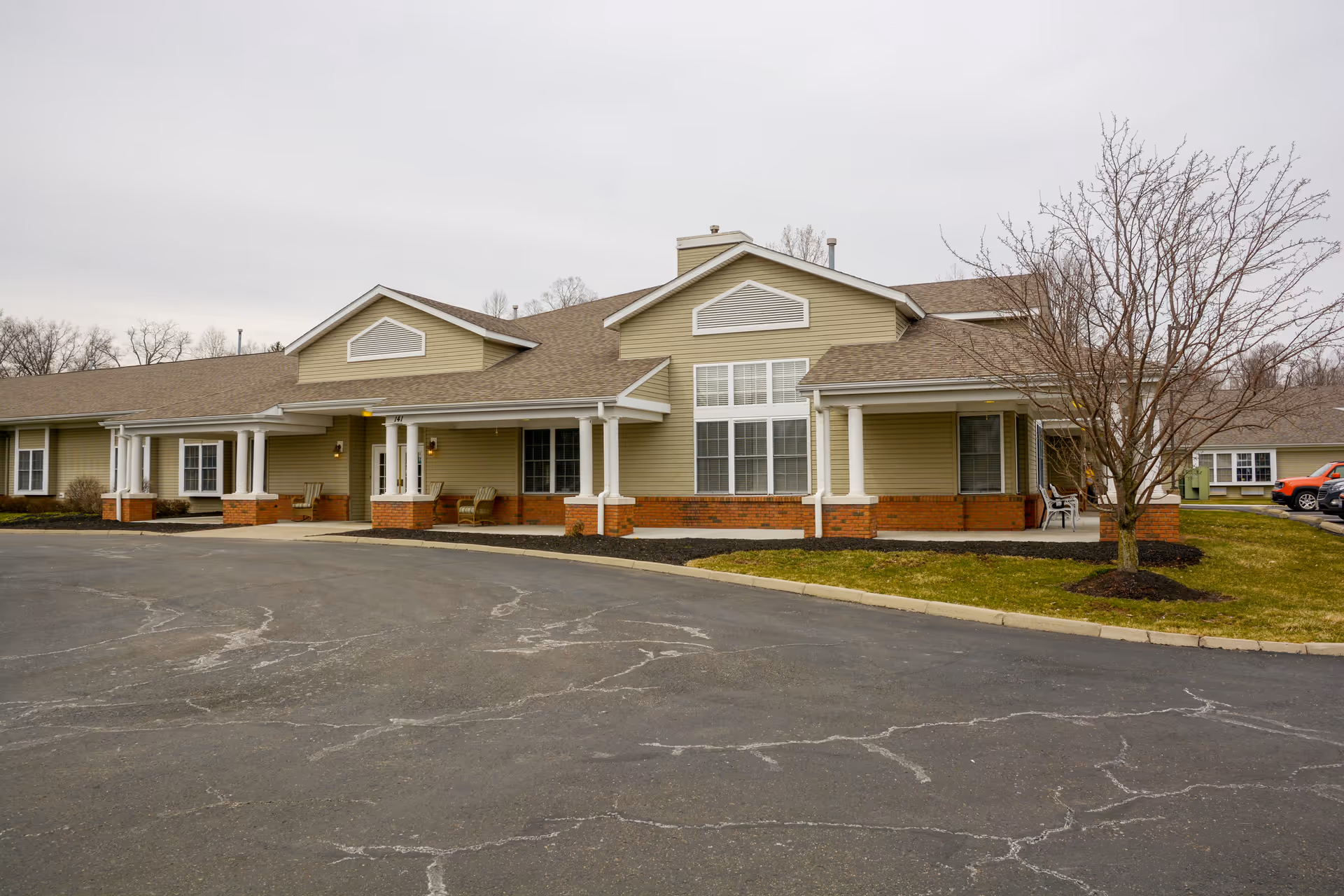 Vista Veranda senior living facility exterior with columns, beige siding, brick base, and parking.