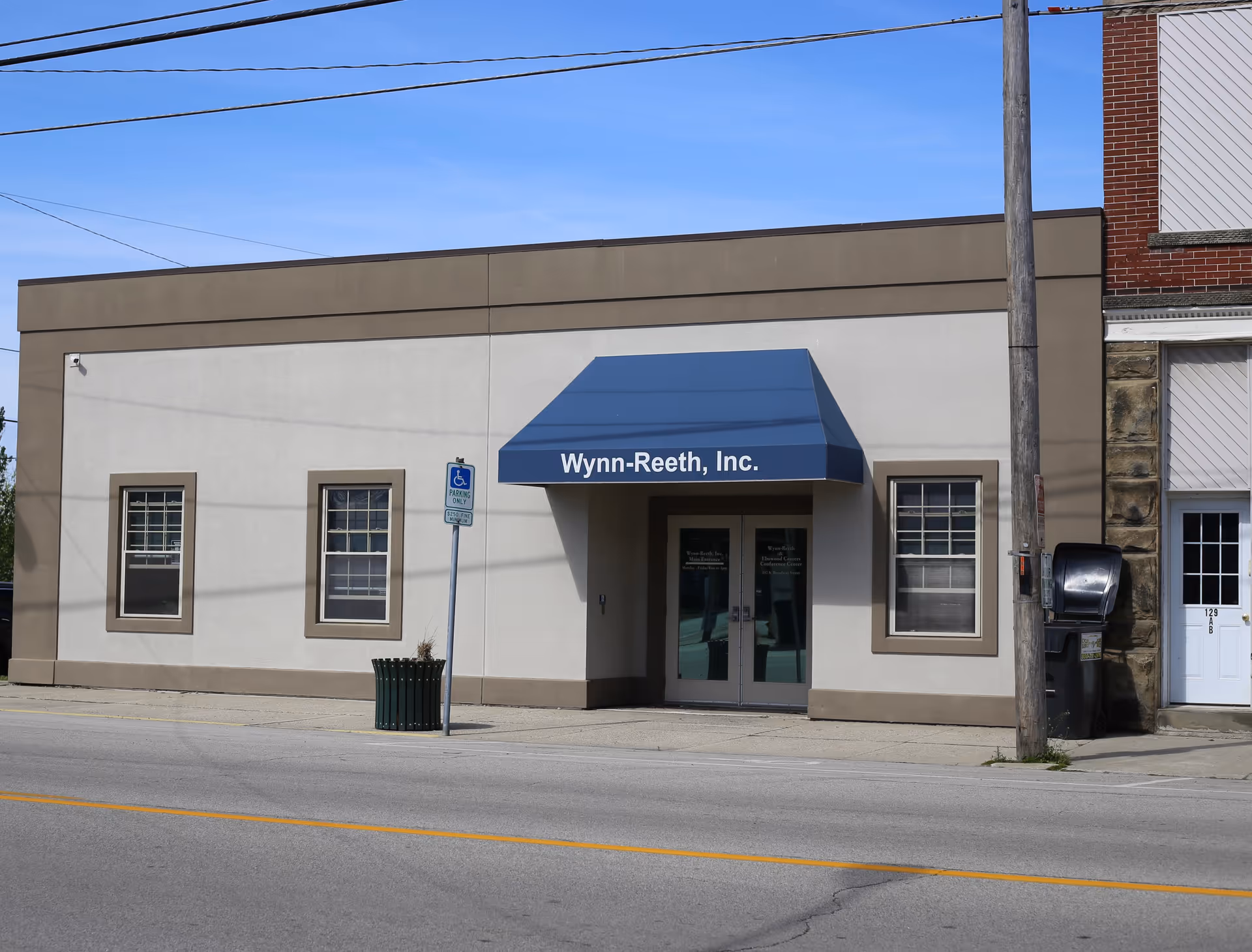 Exterior of Wynn-Reeth, Inc. building with blue awning and glass doors.