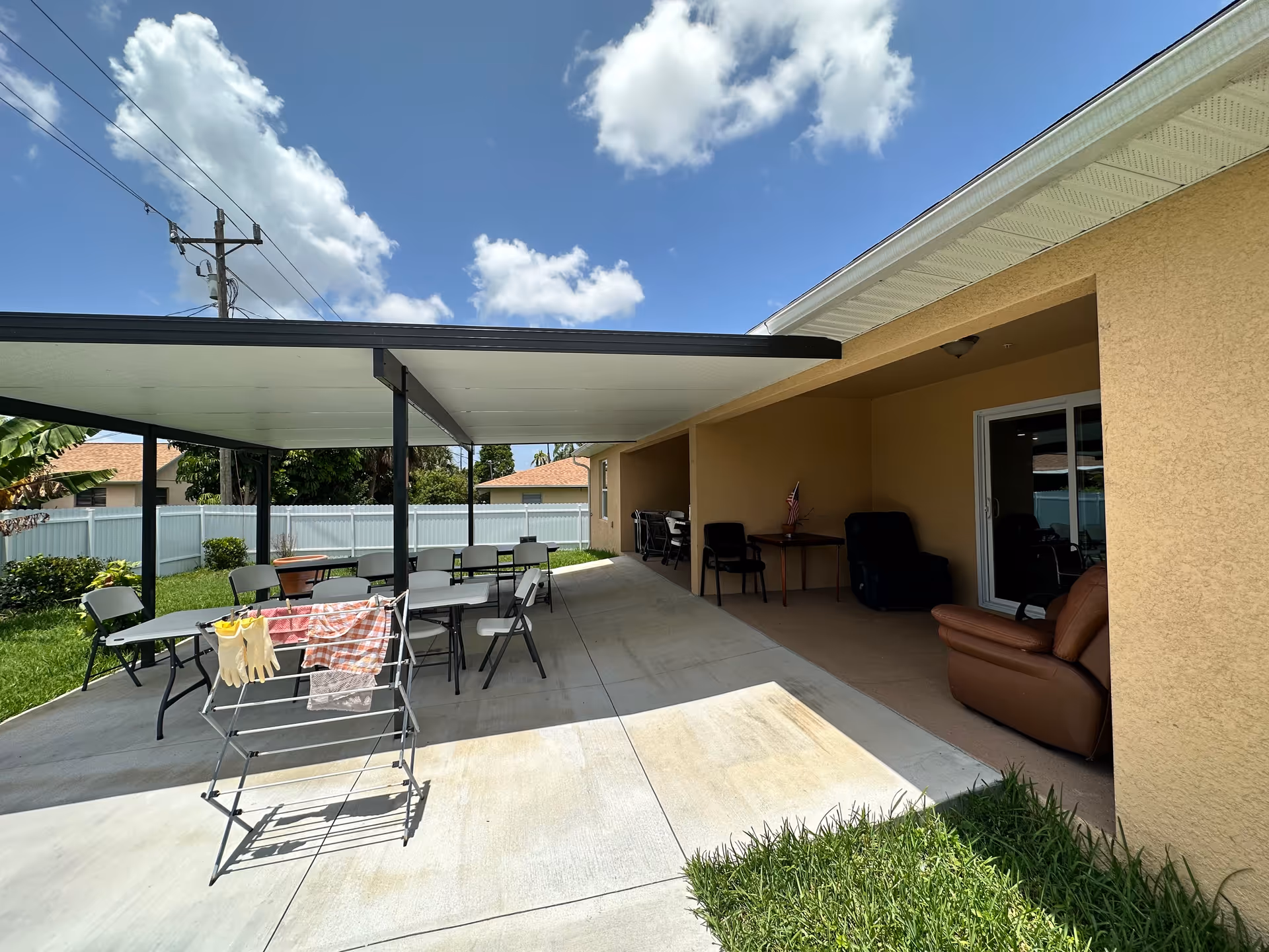 Outdoor covered patio with tables, chairs, and lounge seating beside a beige building.
