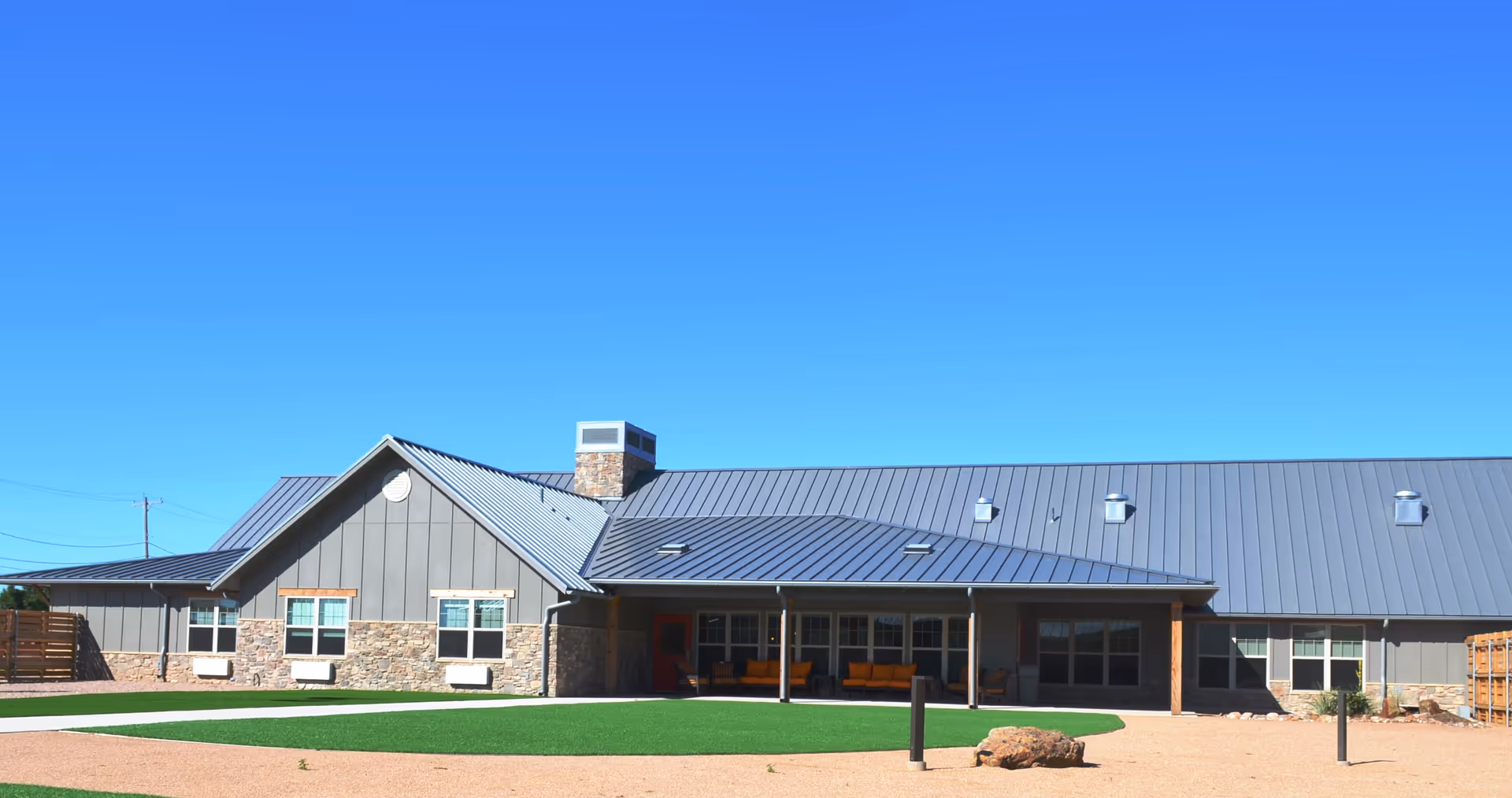 Front exterior of The Crest San Angelo showing stone accents and a metal roof.