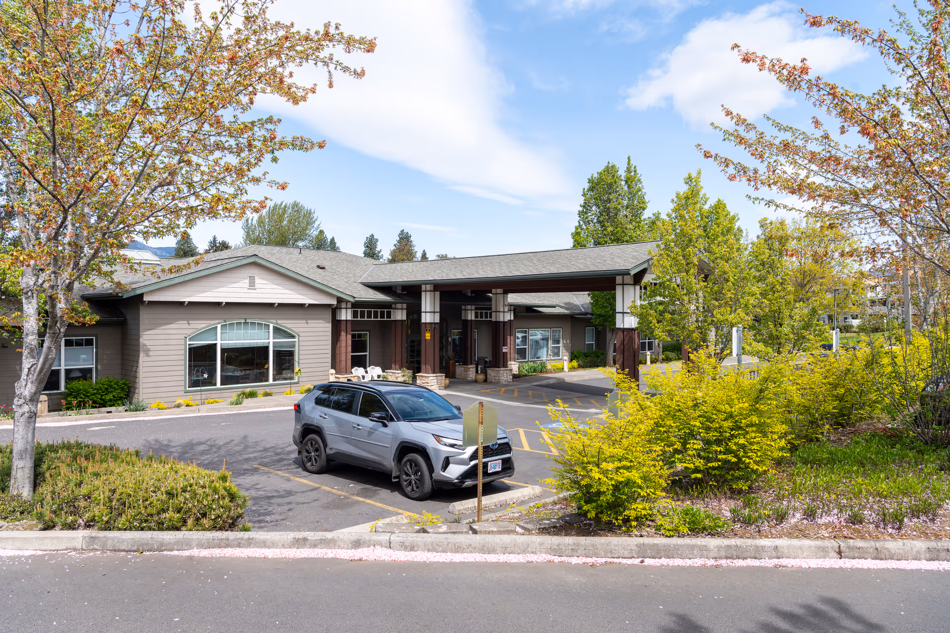 Exterior view of Providence Brookside Manor showing entrance, parking, and landscaped grounds.