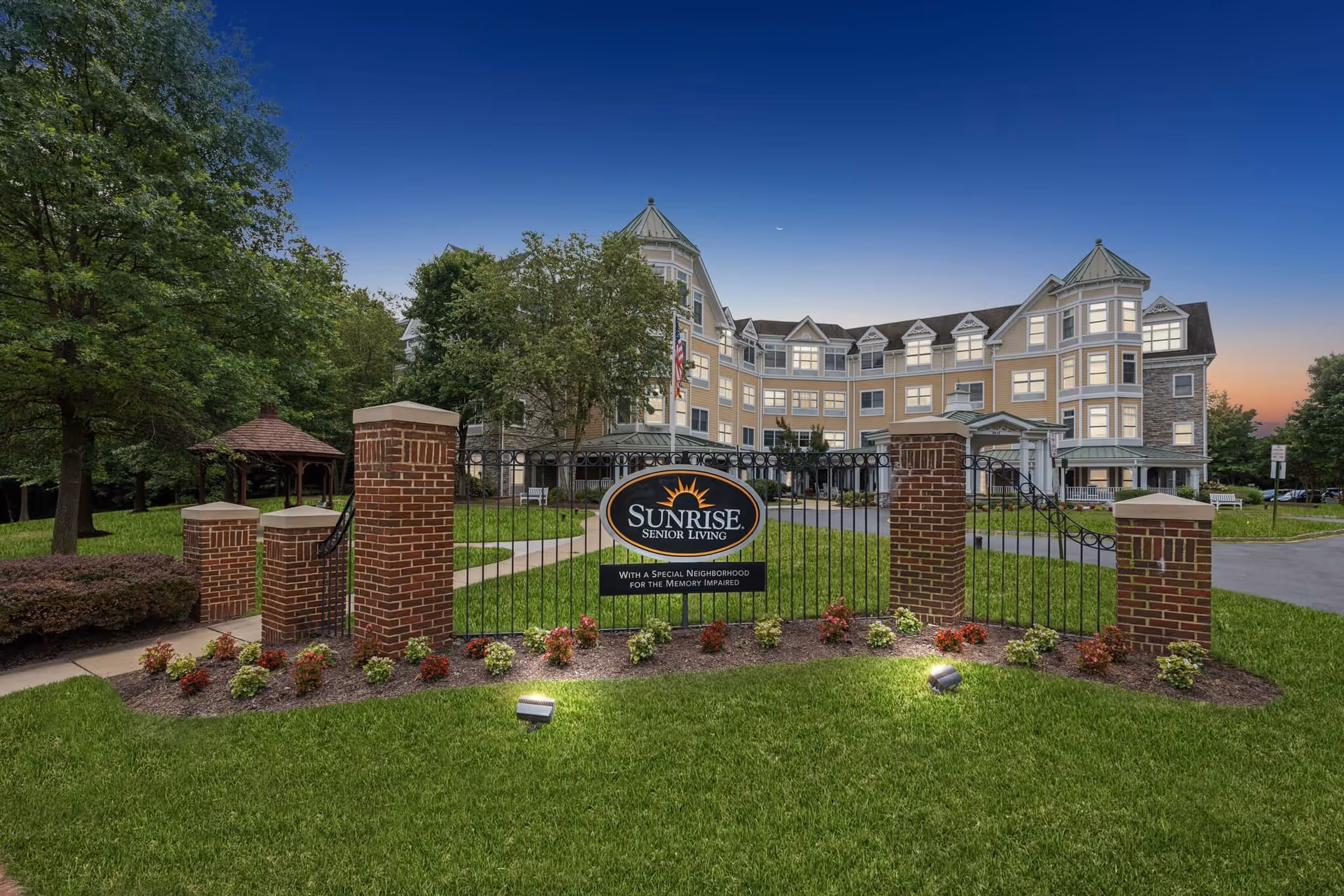 Gated entrance to Sunrise Senior Living with a tan, multi-story building.