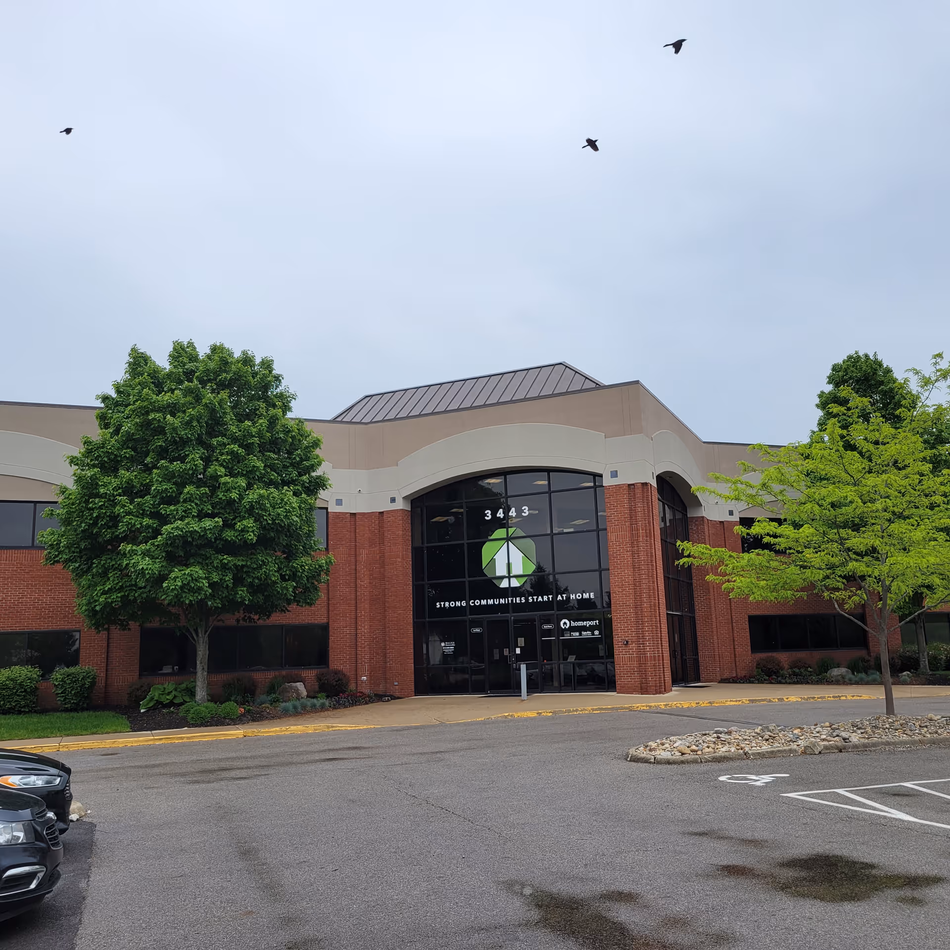 Exterior view of a brick building with a glass front entrance and trees.