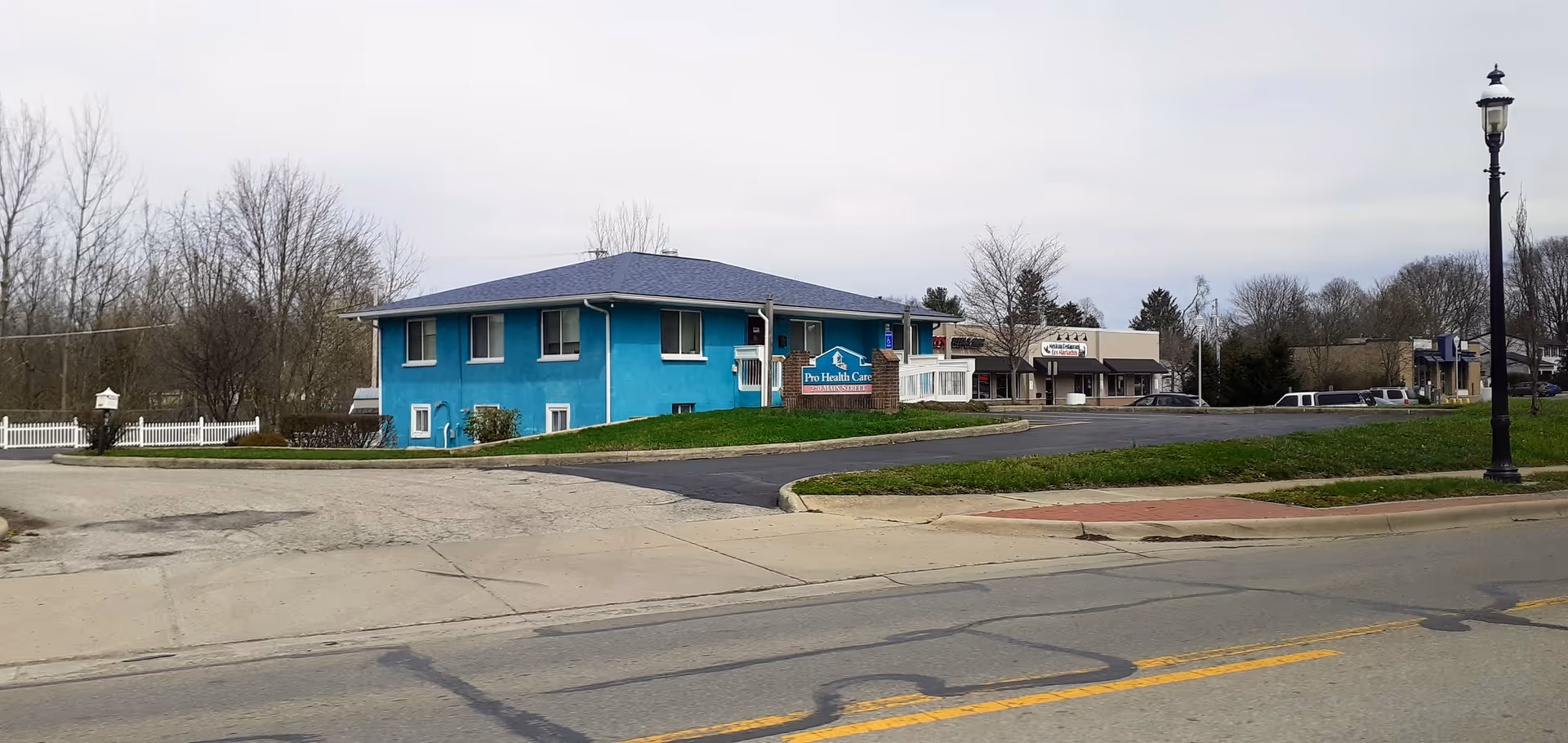 Blue single-story care facility with Pro Health Care Services sign along the street