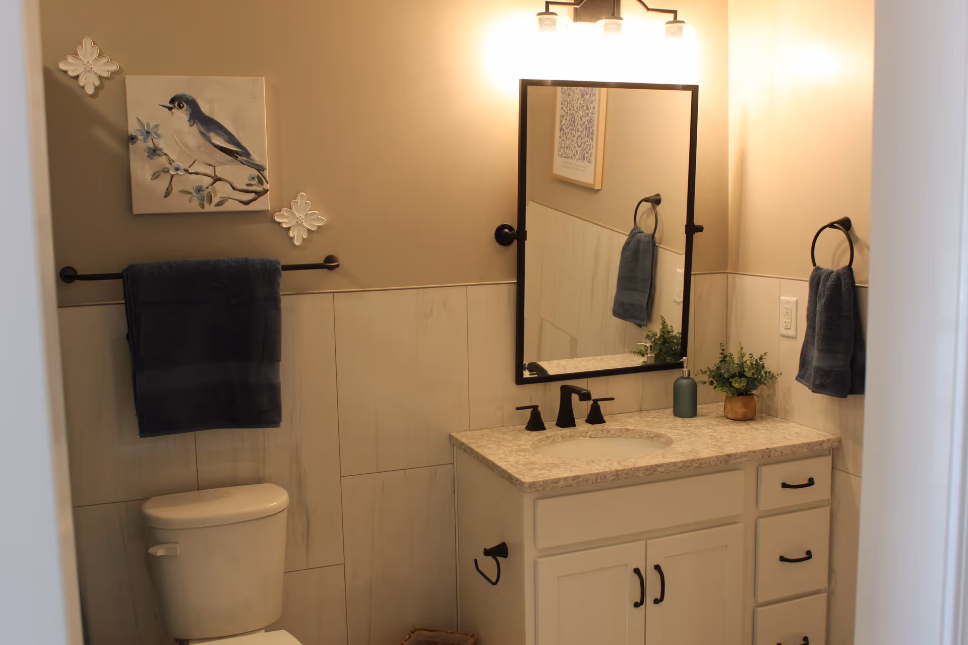 Beige-toned bathroom featuring a vanity, mirror, towels, and a toilet.