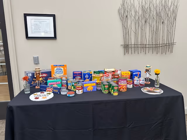 Table with black cloth displaying assorted canned foods and boxes in a facility lobby.