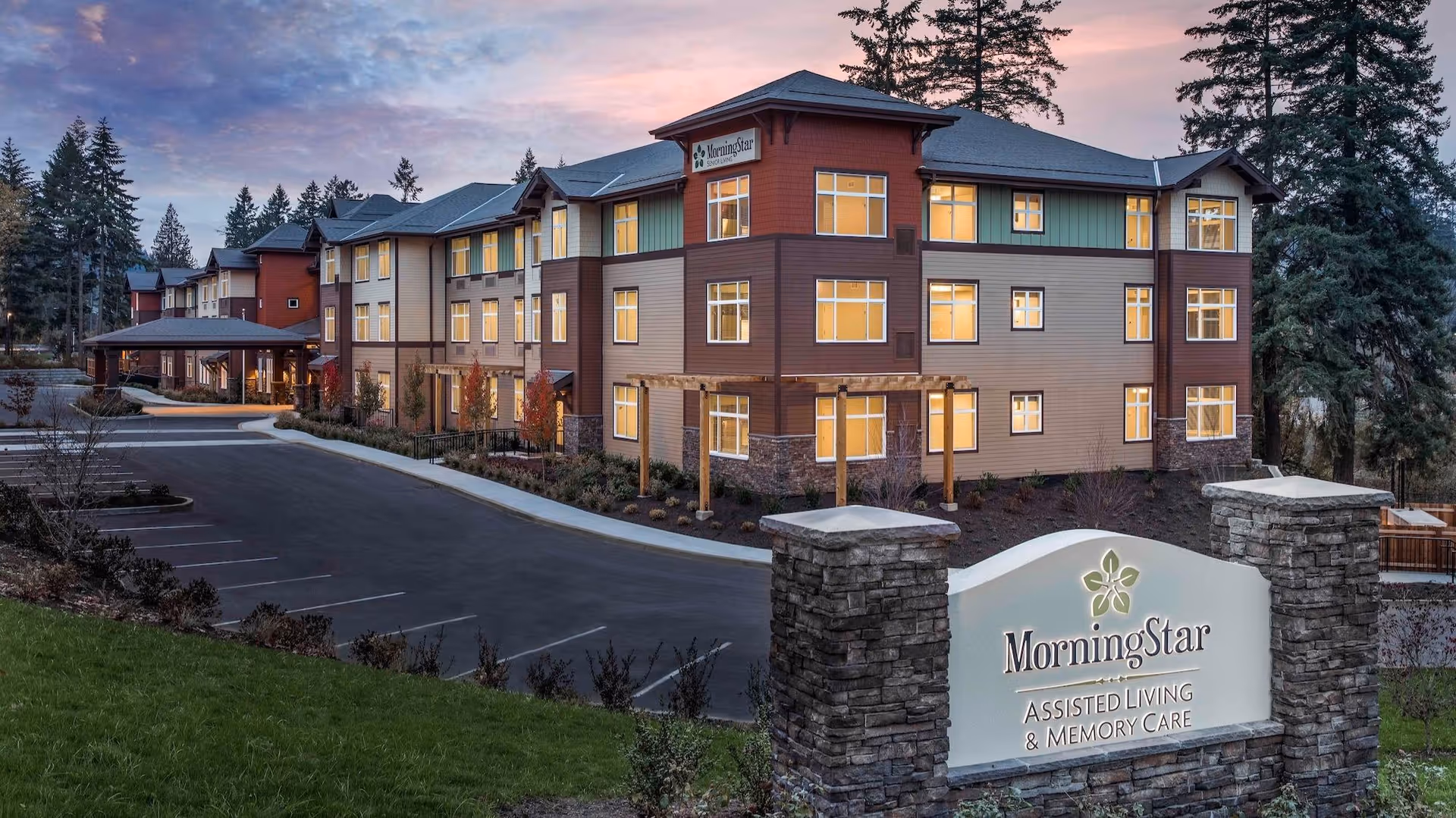 Exterior view of MorningStar Beaverton senior living building at sunset with parking lot and sign.