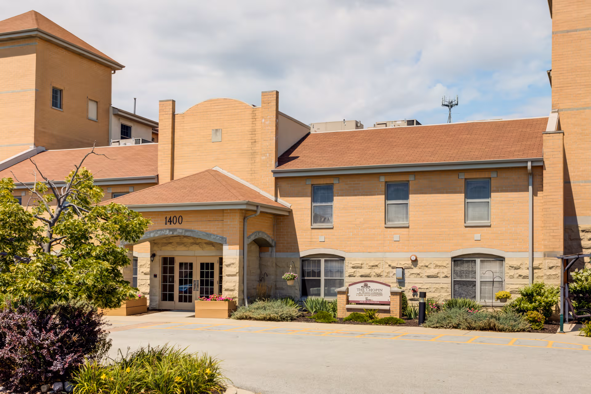 Exterior view of Wilson Commons Assisted Living building with brick facade and landscaped entrance.