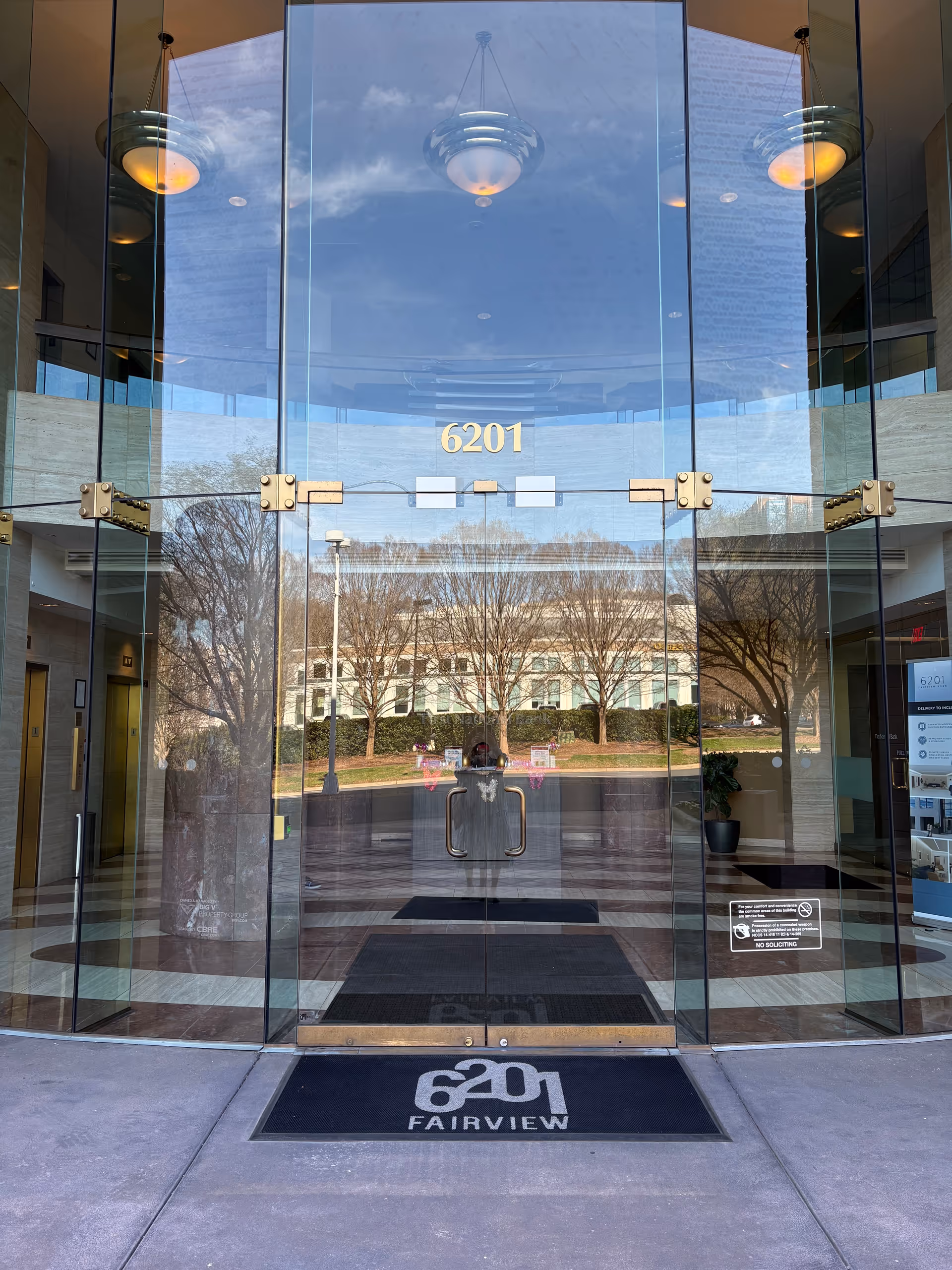 Glass-front building entrance with 6201, reflections, lobby visible beyond