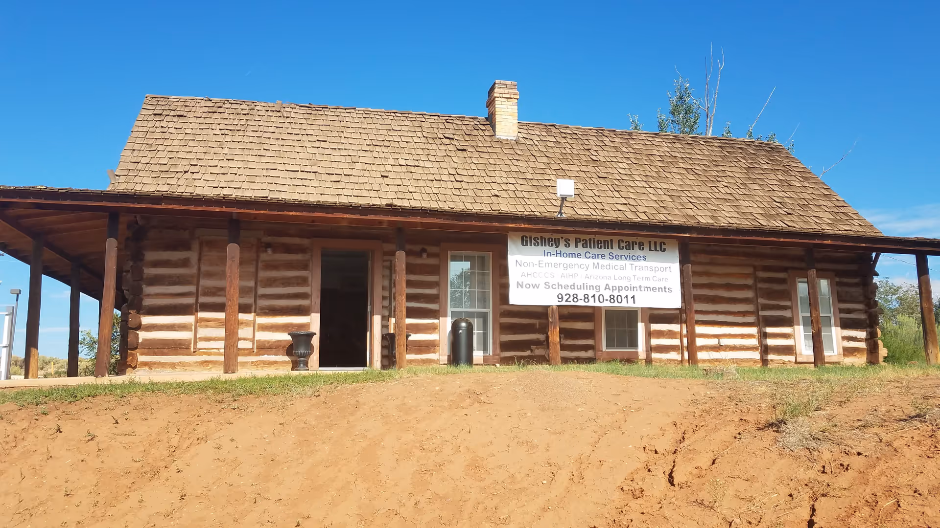 Log cabin-style building with a banner advertising Gishey's Patient Care LLC outside.